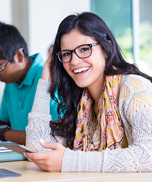 Image of a girl sitting at a desk smiling at the camera.